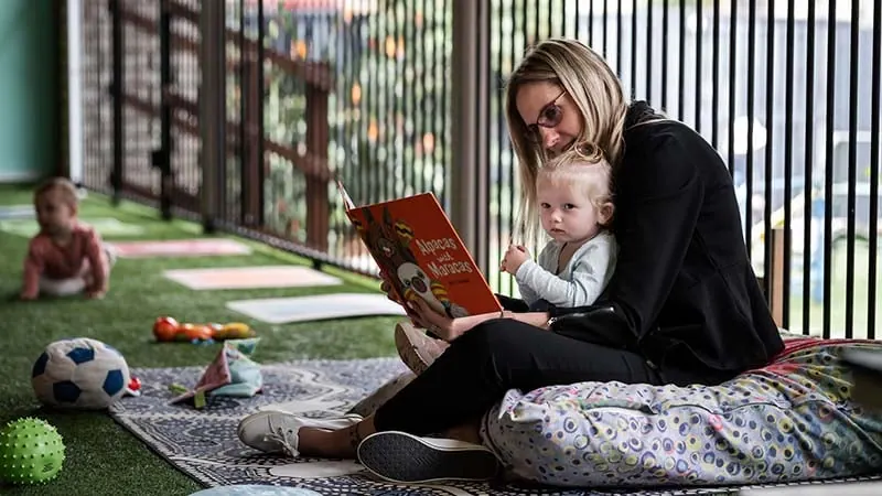 Educator reading a picture book with a young child at Natural Elements Eagleby